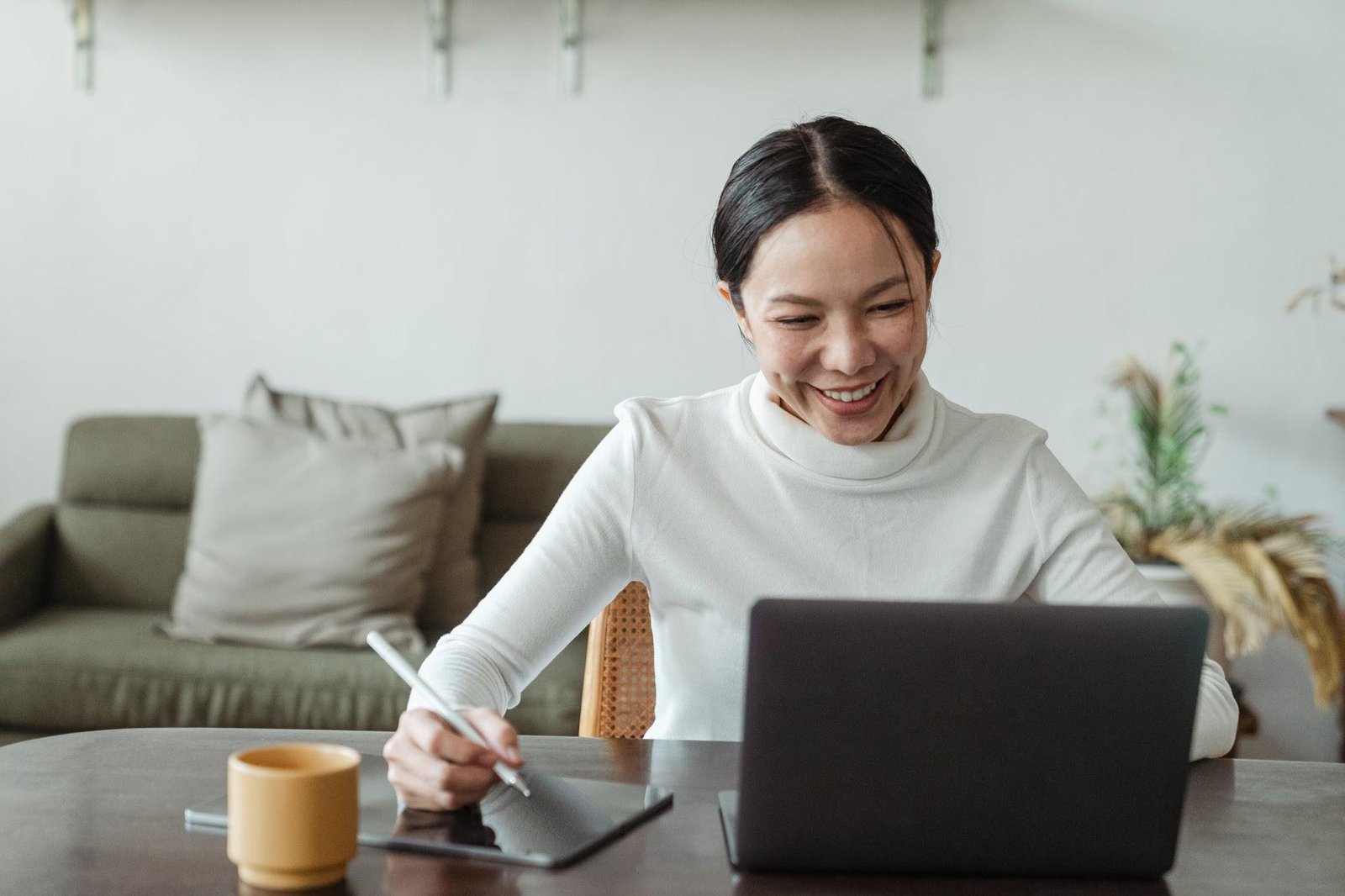 Smiling woman working on tablet while chatting on laptop