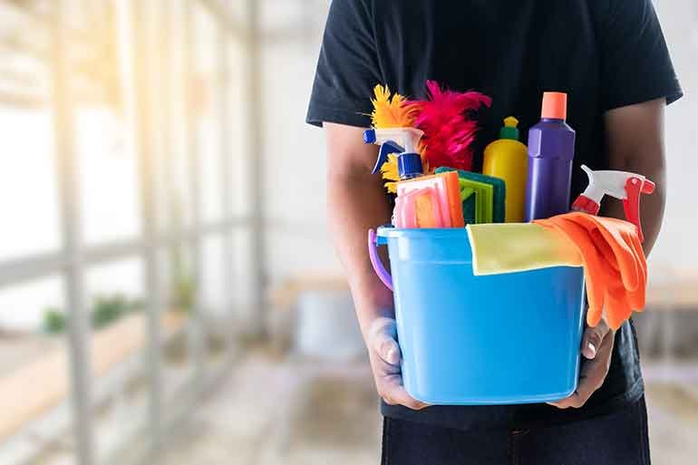 Person holding a bucket of cleaning supplies