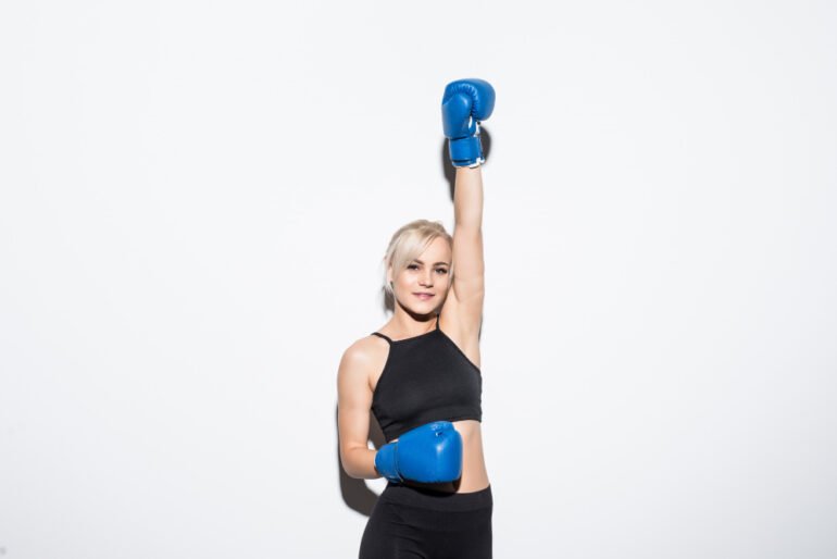 Smiling woman in boxing gloves raising her hand