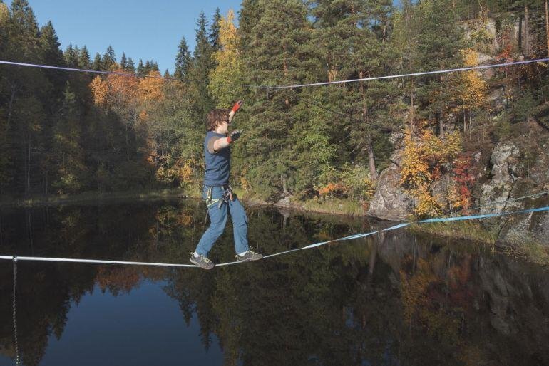 Person walking across Slacklining ropes above a river