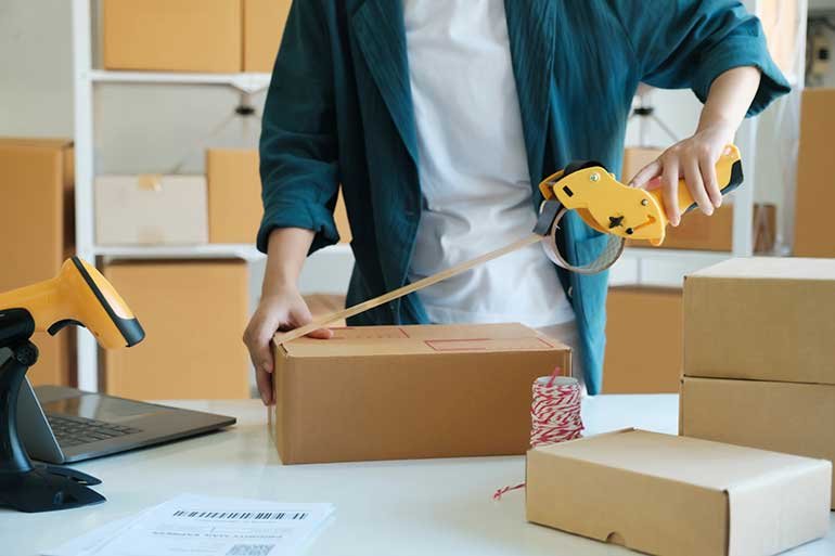 Person taping up a brown cardboard box