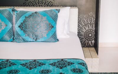 A bed with bright turquoise pillows and top sheet