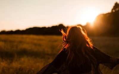 A person standing in a field against the backdrop of a sunset