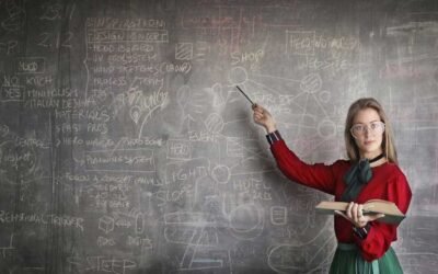 A person standing in front of a blackboard holding a book and pointing