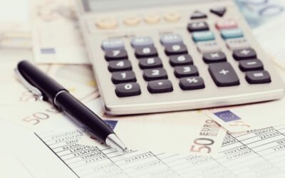 A calculator and pen sitting on a pile of bank notes