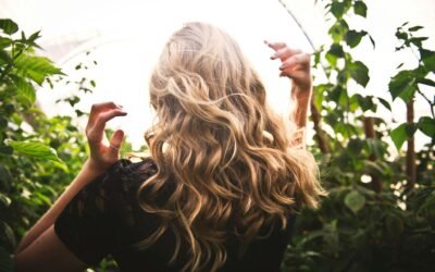 A woman with long blonde hair walking through tall green plants