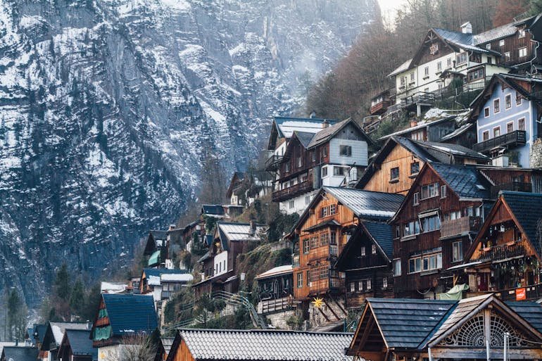 Wooden houses on steep hill by a snow-covered mountain