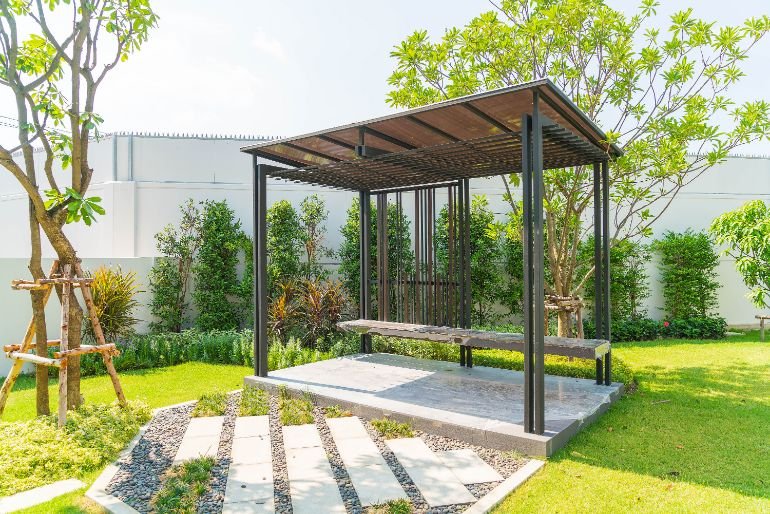 A pergola over a wooden bench in a spacious garden