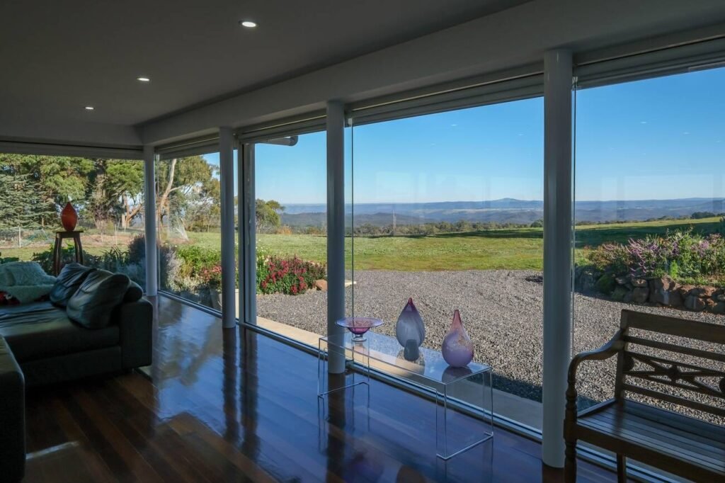 A room with glass windows and a view of the landscape