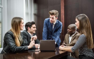 A group of people sitting around a laptop having a meeting