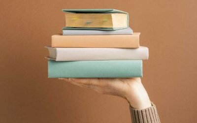 A person holding up a pile of books in one hand